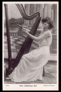 an old black and white photo of a woman playing a harp