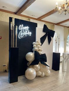 balloons are stacked on top of each other in front of a sign that says happy birthday