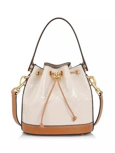 Cinched with a decorative drawstring closure, Tory Burch's bucket bag is crafted of T Monogram embossed patent leather. This piece is accompanied by a flat handle and removable strap for versatile placement..Removable, adjustable strap.Top handle.Drawstring closure.Goldtone hardware.Patent leather.Faux suede lining.Imported.SIZE.8.5'W x 9'H x 5'D.ABOUT THE BRAND.Since debuting her brand in 2004, New York-based designer Tory Burch has made an impact on the fashion world with her handbags and shoes, and playful-yet-polished clothing. Today, Burch remains inspired by color and travel, with her vibrant collections bursting with prints, and her instantly recognizable double-T logo drawing from Moroccan architecture..Cinched with a decorative drawstring closure, Tory Burch's bucket bag is crafte Designer Cream Bucket Bag, Everyday Patent Leather Bag With Detachable Handle, Patent Leather Bag With Detachable Handle For Everyday Use, Luxury Cream Pouch Bucket Bag, Luxury Cream Bucket Bag In Pouch Shape, Tory Burch Bucket Bag, Moroccan Architecture, T Monogram, Bucket Purse