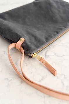 a black and tan purse sitting on top of a marble counter next to a brown strap