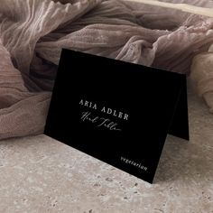 a black business card sitting on top of a table next to a pile of blankets