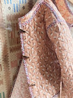 an old quilt is laying on top of a tablecloth covered with pink and white flowers