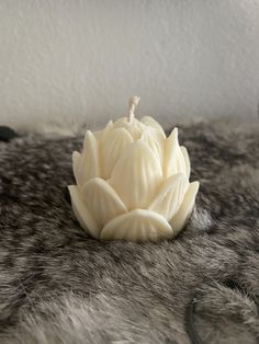 a white candle sitting on top of a fur covered table