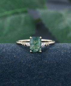 a ring with a green stone surrounded by three white diamonds on top of a blue surface