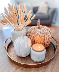 a tray topped with candles and vases on top of a wooden table next to a couch