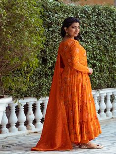 This Set Has a Anarkali, bottom and dupatta. Floral printed tier Anarkali set with hand embroided yoke. It is paired with matching chanderi foil print dupatta enhanced with fabric detailing and palazzo pants. Color: Orange Fabric: Anarkali - Cotton Silk Bottom - Shantoon Dupatta - Chanderi Product Details: Neck Type - Round neck Anarkali Length - 50 inches Bottom Length - 38-40 inches Sleeve Length - 22 inches Note: Available in other colors The product will be delivered within 2-4 weeks of orde Round Neck Anarkali, Floral Print Anarkali, Fabric Detailing, Silk Anarkali, Orange Floral Print, Silk Bottoms, Orange Fabric, Fashion App, Foil Print