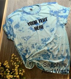 a t - shirt with the words your text here on it is laying next to some flowers