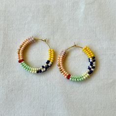 Welcome to Mint Handmade ❤ These handwoven hoop earrings are a stunning piece of craftsmanship, perfect for adding vibrant color to any outfit. Each pair is meticulously made with high-quality Czech glass beads and gold stainless steel ear wires. Key Features: Materials: High-quality Czech glass beads, gold stainless steel ear wire Diameter: Earring ring diameter is 2.5 cm Care Instructions: Avoid contact with water, chemicals, and perfumes Why You'll Love Them: Vibrant Colors: Perfect for addin Artisan Multicolor Round Beaded Earrings, Adjustable Multicolor Woven Beaded Earrings, Multicolor Woven Adjustable Beaded Earrings, Colorful Round Bead Earrings For Everyday, Handmade Beaded Hoop Earrings For Beach, Handmade Hoop Beaded Earrings For Beach, Colorful Round Beads Earrings For Everyday, Handmade Artisan Multicolor Hoop Earrings, Artisan Handmade Multicolor Hoop Earrings