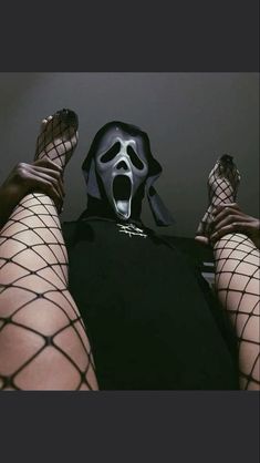 a person wearing a mask and fishnet stockings with their feet up in the air