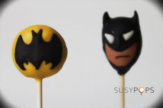 two lollipops with batman faces on them, one is yellow and the other is black