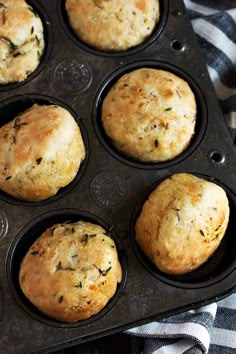 four muffins in a black tray on a table