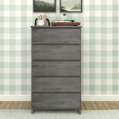 a dresser with two pictures on the wall above it