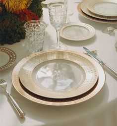 the table is set with white and gold plates, silverware, and flowers in vases