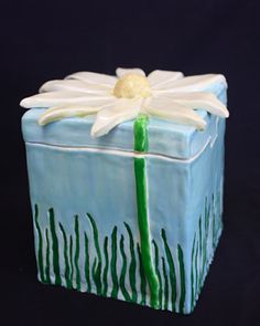 a blue and white box with a flower on the top is sitting on a black surface