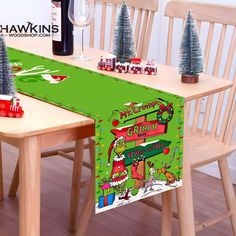 a christmas table runner with santa clause on it next to two wooden chairs and a bottle of wine