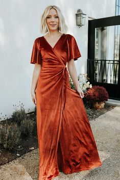 a woman wearing an orange velvet wrap dress