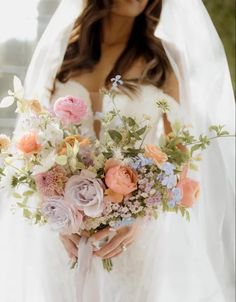 a woman in a wedding dress holding a bridal bouquet with pink, orange and blue flowers