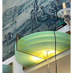 a green lamp is on top of a shelf in front of a wall with paintings