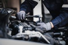 a mechanic working on the engine of a car with his hands on the valve cover