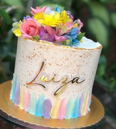 there is a cake that has flowers on the top and rainbow icing around it