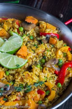 a pan filled with rice and vegetables on top of a wooden table