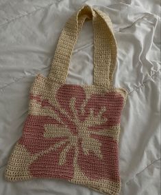 a crocheted bag sitting on top of a white bed next to a pillow