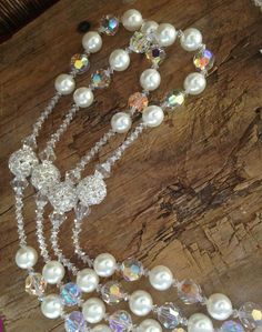 a necklace with pearls and crystal beads on a wooden table next to other jewelry items