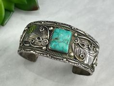 "A beautiful vintage Navajo sterling silver cuff bracelet with a vibrant light blue turquoise stone. Marked \"Thomas J, Sterling.\" Measures bout 1.09\" wide and about 6.75\" around on the inside, including the gap. Some wear and tarnish. May be slightly adjustable due to the way it's made, but I do not guarantee, and I do not accept returns of adjusted items. Props shown in photos is for display purposes only, not included in this listing. As always, satisfaction is guaranteed. Thanks for shopp Turquoise Stamped Bangle, Turquoise Stamped Cuff Bracelet Collectible, Artisan Turquoise Engraved Bracelet, Stamped Turquoise Bracelet, Artisan Turquoise Engraved Bracelets, Turquoise Stamped Bracelet, Engraved Turquoise Bracelet, Engraved Turquoise Bracelet Jewelry, Engraved Turquoise Jewelry Bracelet