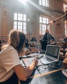 a woman sitting at a table with a laptop computer in front of her on top of a desk