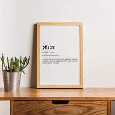 a potted plant sitting on top of a wooden table next to a framed poster