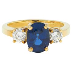 an oval sapphire and diamond three stone ring in yellow gold with two diamonds on each side