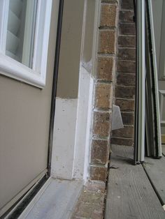 the corner of a house with an open door and window on the outside, next to it is a brick wall that has been ripped off