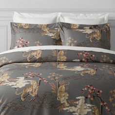 a bed covered in grey and white comforter with tiger designs on the coverlet