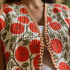 a woman wearing an orange and white floral jacket