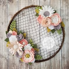 a wreath made out of paper flowers sitting on top of a wooden table next to a wire net