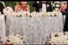 two people sitting at a table with white flowers