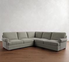 a large gray couch sitting on top of a wooden floor next to a white wall