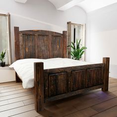 a bed with wooden headboard and foot board on hardwood floor next to potted plant