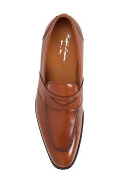 A notched keeper strap enhances the distinctive look of this suave apron-toe loafer crafted of burnished calfskin and finished with hand stitching. Leather upper, lining and sole Made in Italy Designer Shoes Fitted Wingtip Moccasins With Leather Sole, Fitted Leather Tassel Loafers With Leather Sole, Fitted Leather Sole Plain Toe Moccasins, Fitted Leather Sole Moccasins With Plain Toe, Fitted Leather Moccasins For Semi-formal Occasions, Leather Sole Moccasins, Elegant Fitted Wingtip Moccasins, Elegant Fitted Leather Tassel Loafers, Elegant Moc Toe Bridle Leather Shoes