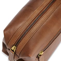 a brown leather toiletry bag with zippers on the front and side zips