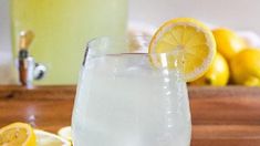 a glass filled with lemonade sitting on top of a table next to sliced lemons