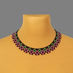 a pink, green and black beaded necklace on a mannequin neckline