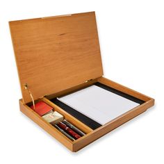 an open wooden box with papers and pens in it