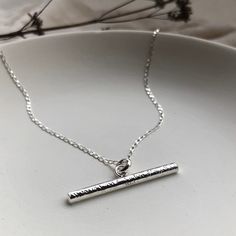 "The Luna T Bar Necklace is a modern twist on a classic jewellery piece. As with all my jewellery it has been handcrafted, with love, in small batches from my Brighton workshop. This necklace is made using recycled sterling silver and comes on an 18\" fine diamond cut curb chain. The T bar measures approximately 3cm from end to end and is 3mm thick. This necklace is perfect for everyday wear as a stand alone piece and also looks great layered up with other necklaces. The textured surface is particularly striking when the light catches it giving it a lovely shimmering appearance. The perfect gift for someone special, whether that's you or a loved one. All of my jewellery comes wrapped in recycled and 100% recyclable white pillow boxes and colourful recycled tissue. All of my packaging is 10 Silver Sterling Silver Bar Necklace With Rectangular Pendant, Silver Dainty Bar Necklace For Everyday, Silver Bar Necklace With Delicate Chain For Everyday, Minimalist Silver Engraved Bar Necklace, Dainty Sterling Silver Bar Necklace For Everyday, Simple Silver Necklace With Rectangular Pendant, Everyday Silver Bar Necklace With Delicate Chain, Minimalist Engraved Silver Bar Necklace, Minimalist Silver Bar Necklace As Gift