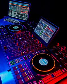 two laptops sitting on top of a dj's desk