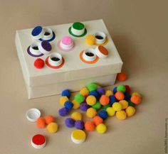 a box filled with lots of different colored pom poms on top of a table