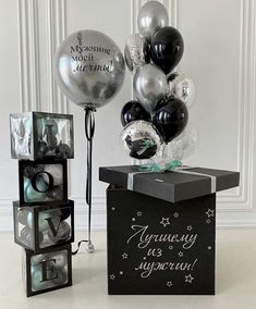 a black box filled with balloons next to a bunch of silver and black boxes that say i love you