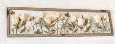 a wooden frame with flowers in it hanging on the wall