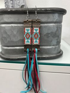 two pairs of beaded earrings hanging from hooks on a metal potted planter