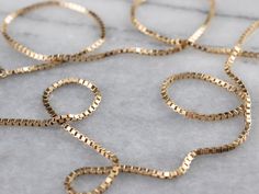 This classic box chain necklace is crafted from highly polished gold. Each link creates a fluid play of light that almost seems to sparkle when worn. This is a versatile piece that would look lovely worn alone or strung with a pendant. Metal: 14K Yellow Gold Width of Chain: 1.4 mm Length of Chain: 23 Inches Marks: "BVL 14K" Stamped on the clasp Cheap Yellow Gold Box Chain Jewelry, Classic Box Chain Necklaces, Luxury Classic Box Chain Necklace, Luxury Gold Plated Box Chain Necklaces, Box Chain Necklace, Gold Chain With Pendant, Basic Jewelry, Right Hand Rings, Layered Chains